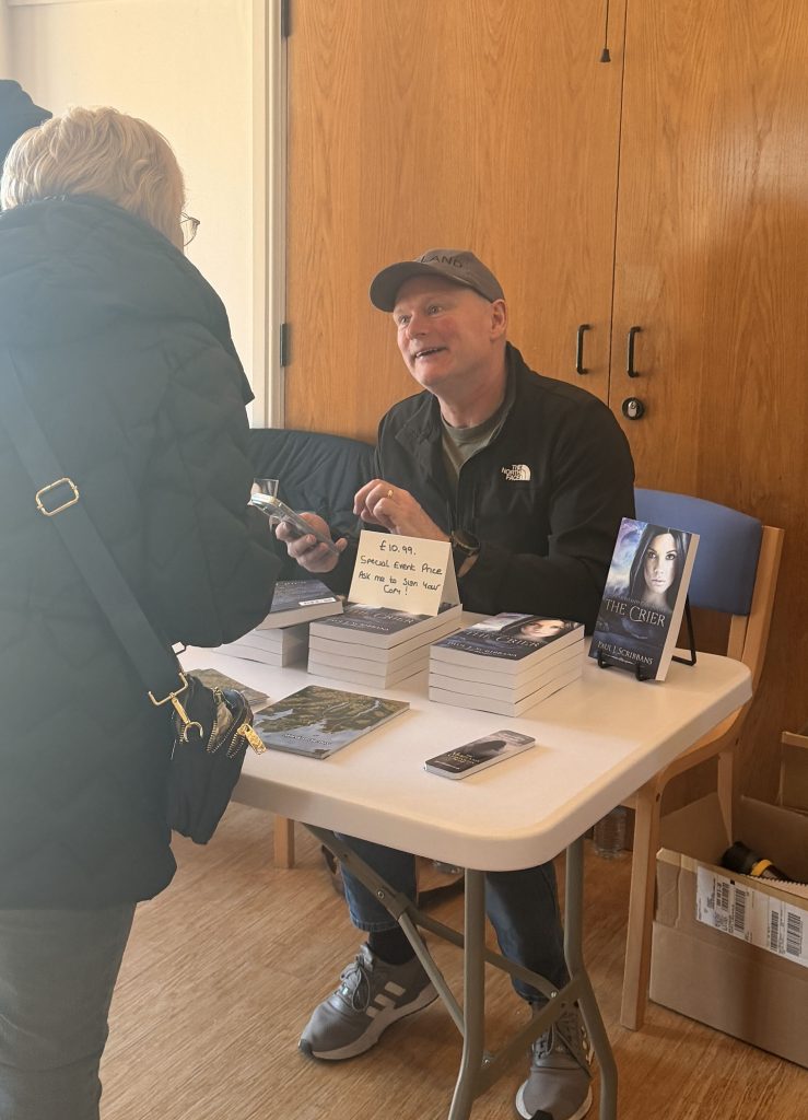 P.J. Scribbans speaking with a visitor at the Furness Book Fair at Swarthmoor Hall.